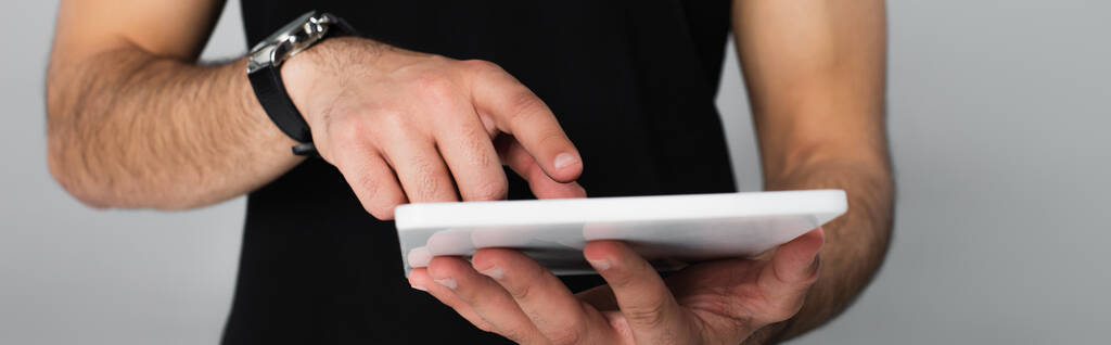 częściowy widok młodego mężczyzny w czarnej koszulce wskazujący na cyfrowy tablet odizolowany na szaro - Zdjęcie, obraz