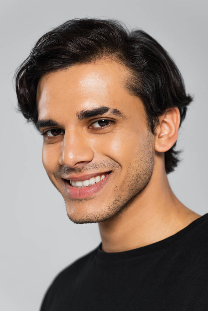 jovem sorridente homem em preto t-shirt posando isolado no cinza - Foto, Imagem
