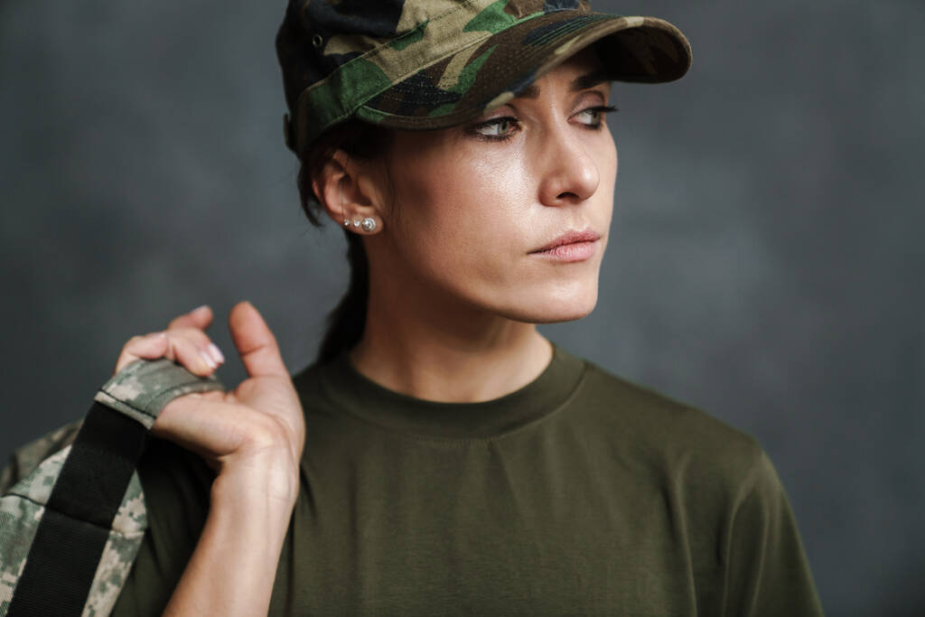 Serieuze mooie soldaat vrouw poseren met tas binnen - Foto, afbeelding
