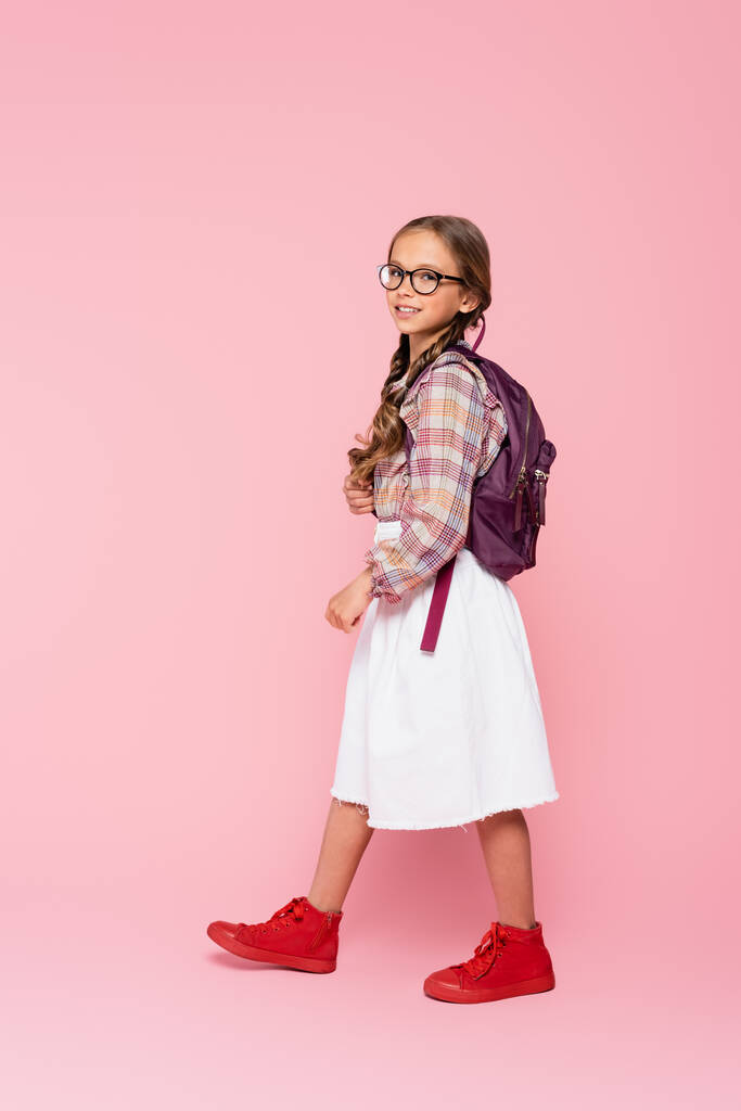 笑顔女子高生でスカート歩く上のピンクの背景  - 写真・画像