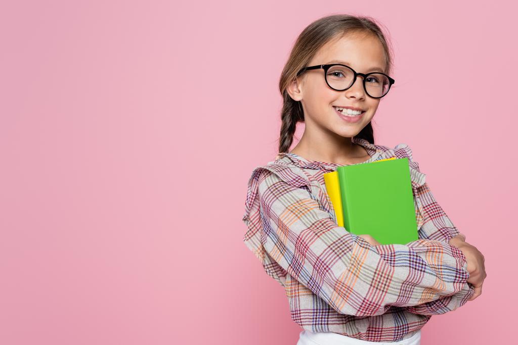 cheerful girl with textbooks smiling at camera isolated on pink - Photo, image