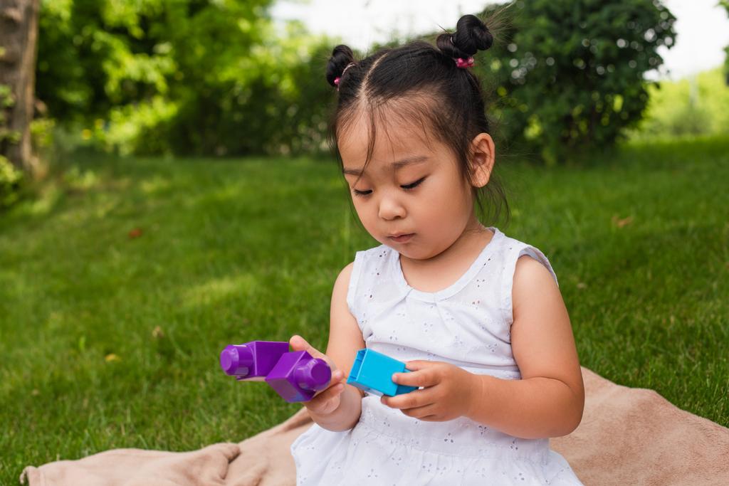 azjatycki dziecko w sukienka zabawy klocki w park  - Zdjęcie, obraz
