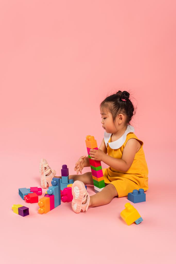 barna ázsiai kisbaba lány ruha játszik építőkockák rózsaszín  - Fotó, kép