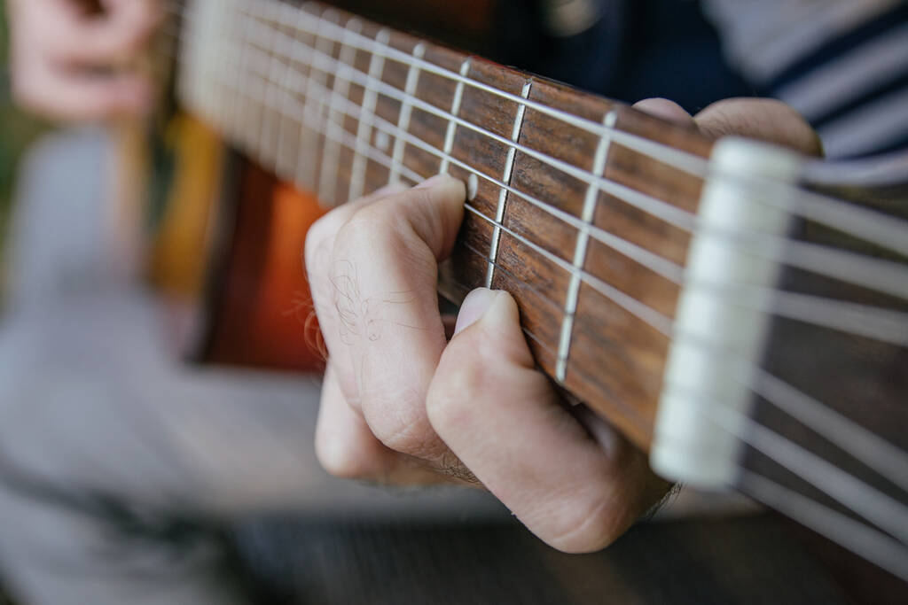 detailní záběr na kytaru hrající s mužskou rukou hrající na struny - Fotografie, Obrázek