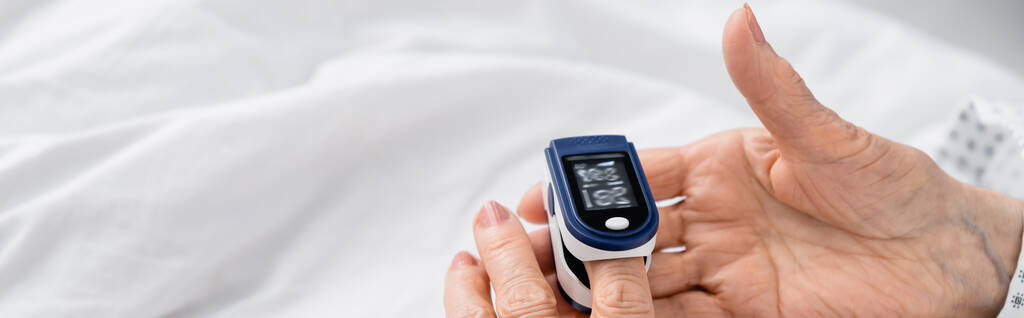 病院のベッド、バナーにデジタル酸素計を使用して高齢女性の作物ビュー  - 写真・画像