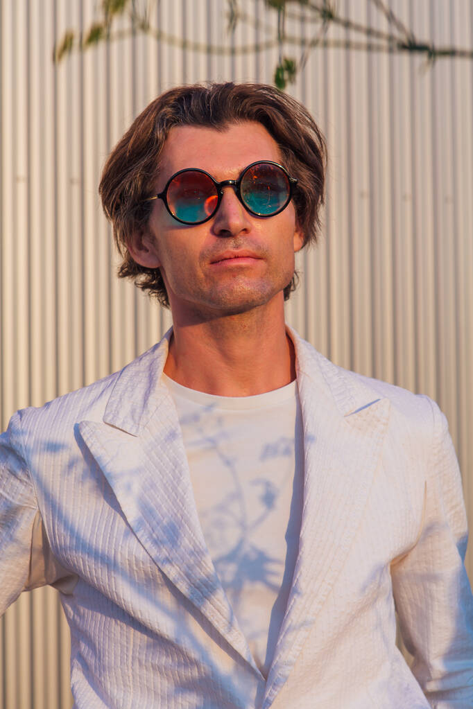 Крупный план портрета красивого мужчины в круглых хиппи солнцезащитных очках на закате - Фото, изображение