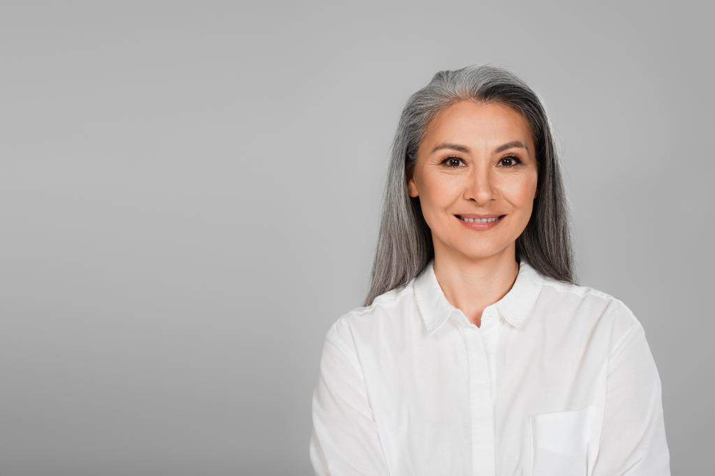 alegre asiático mulher no branco camisa sorrindo para câmara isolado no cinza - Foto, Imagem
