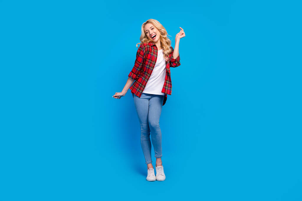 Fotografie okouzlující funky mladá žena oblečená kostkovaná košile tanec s úsměvem izolované modré barvy pozadí - Fotografie, Obrázek