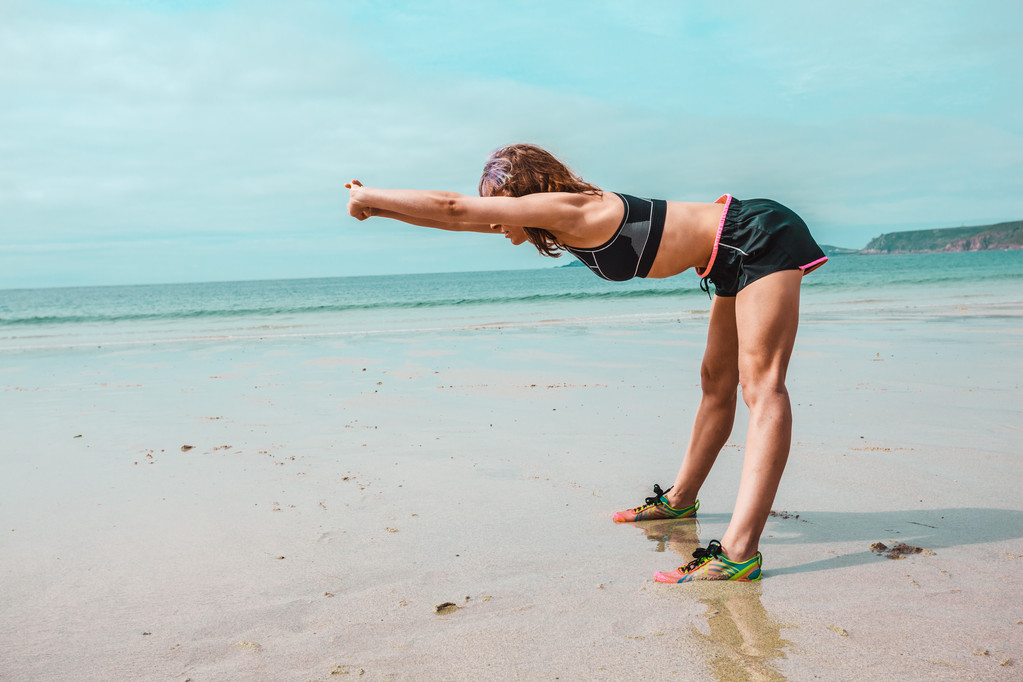 Mujer atlética joven estirándose en la playa
 - Foto, Imagen