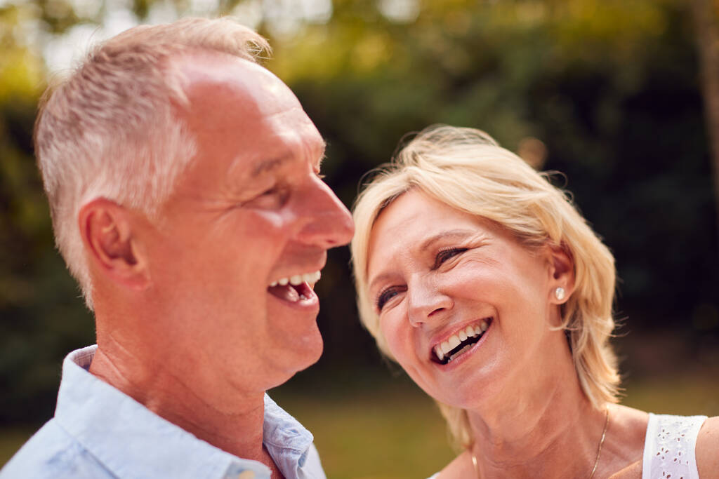 Retrato de la pareja mayor riéndose en el jardín en casa juntos - Foto, Imagen