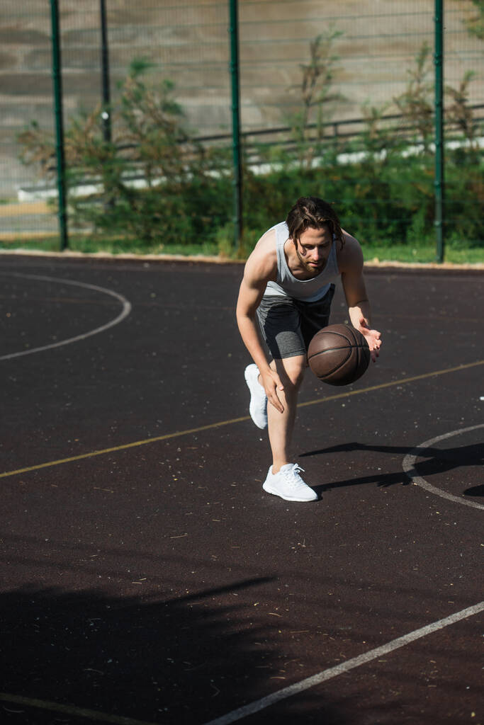 若いスポーツマンは屋外の遊び場でバスケットボールをしています  - 写真・画像