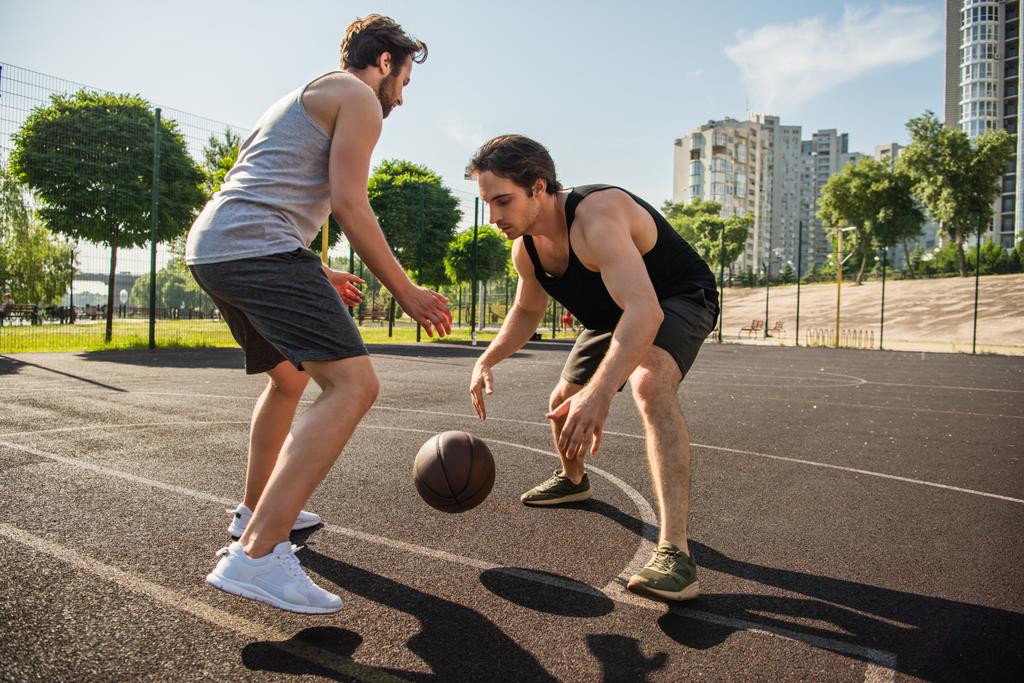 スポーツウェアの男性のサイドビューは屋外コートでバスケットボールをプレイ  - 写真・画像