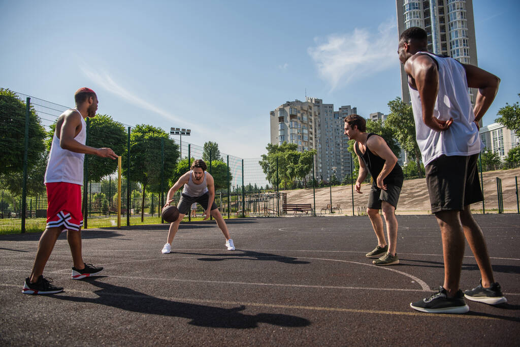 Homem jogando basquete com amigos inter-raciais no playground  - Foto, Imagem
