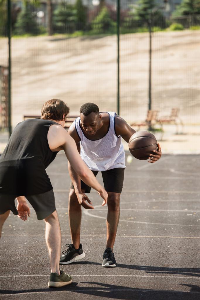 Afrika kökenli Amerikalı bir adam oyun alanında arkadaşıyla basketbol oynuyor.  - Fotoğraf, Görsel