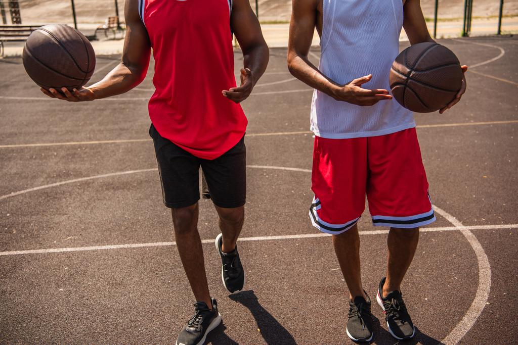 Vista recortada de jugadores de baloncesto afroamericanos caminando en un parque infantil al aire libre  - Foto, imagen