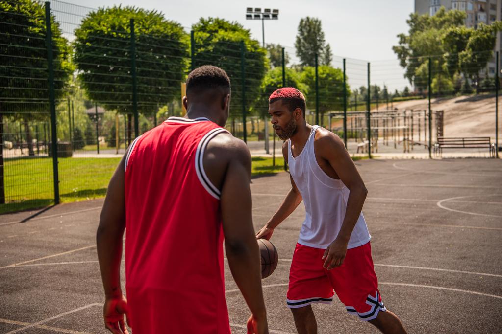 Молодий афроамериканець грає в баскетбол поруч з другом на ігровому майданчику.  - Фото, зображення