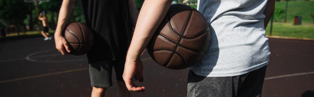 屋外でバスケットボールボールを保持している男性の作物ビュー、バナー  - 写真・画像