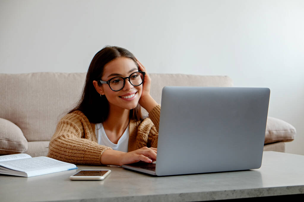 Online oktatási koncepció. Egy fiatal, gyönyörű barna nő szemüveget visel, és részt vesz egy csoportos videohíváson. Egy főiskolai hallgató portréja, aki otthon tanul. Közelkép, másolás tér, háttér. - Fotó, kép