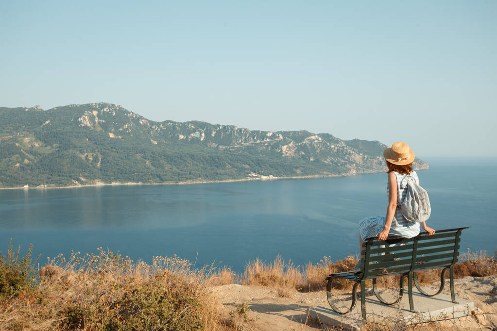 girl tourist sitting on a bench at  the observation deck and looks at the sea and a beautiful landscape, Corfu Island in Greecethe sea - Photo, Image
