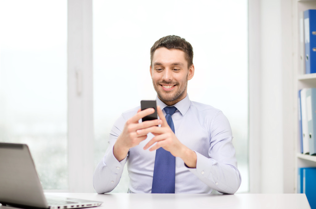 Homme d'affaires avec ordinateur portable et smartphone au bureau - Photo, image