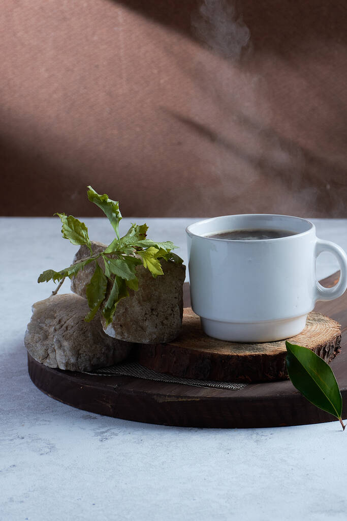 Μια κάθετη λήψη ενός φλιτζανιού καφέ σε μια ξύλινη σανίδα με πέτρες και ένα κλαδί - Φωτογραφία, εικόνα