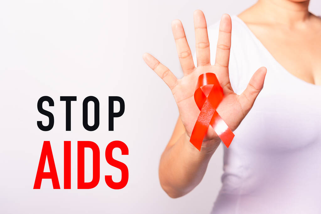 Szoros kép a nő piros szalaggal Támogatja a HIV AIDS kéznél, Stop AIDS, World AIDS Day és az orvostudomány koncepció másolási hely használható fehér háttér - Fotó, kép