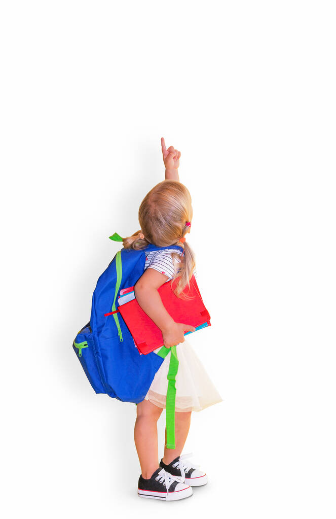 Маленькая девочка с синим рюкзаком с указательным пальцем на белом фоне. - Фото, изображение