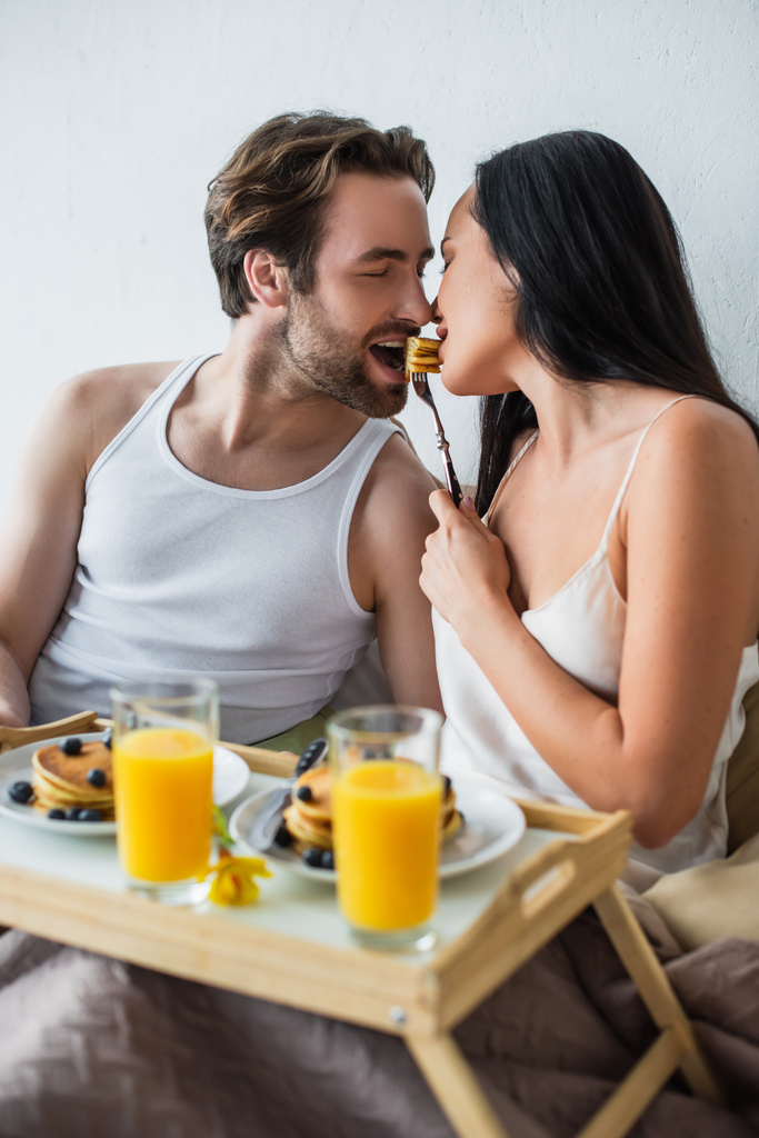couple heureux manger des crêpes de la même fourchette au lit - Photo, image