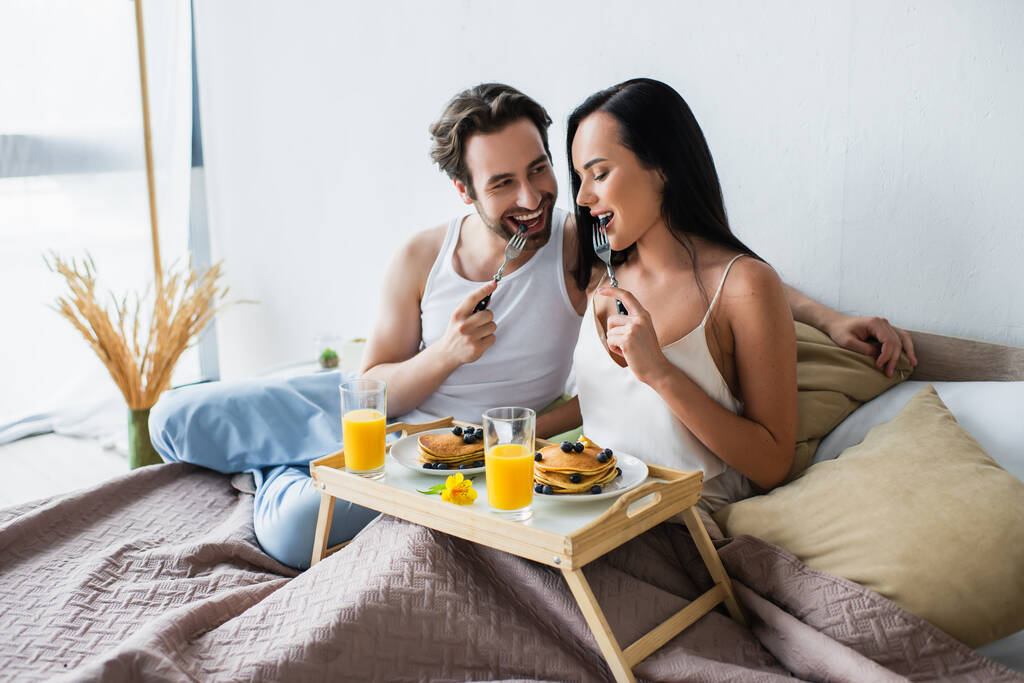 örömteli pár finom reggelit fogyaszt az ágyban - Fotó, kép