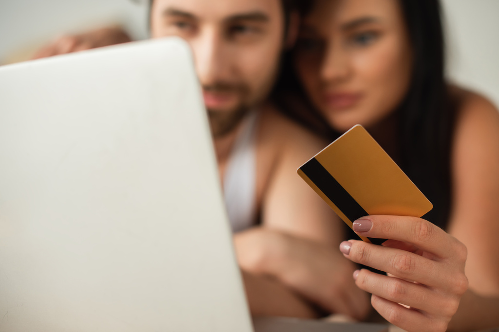 θολή ζευγάρι κρατώντας πιστωτική κάρτα κοντά στο φορητό υπολογιστή, ενώ ψώνια σε απευθείας σύνδεση  - Φωτογραφία, εικόνα
