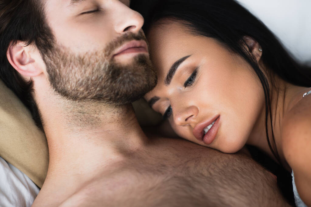 Genç bir kadın üstsüz erkek arkadaşının göğsünde yatıyor.  - Fotoğraf, Görsel