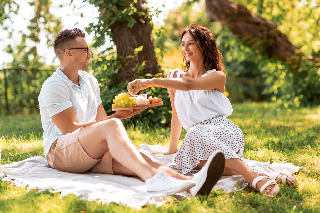 šťastný pár s piknikem v letním parku - Fotografie, Obrázek