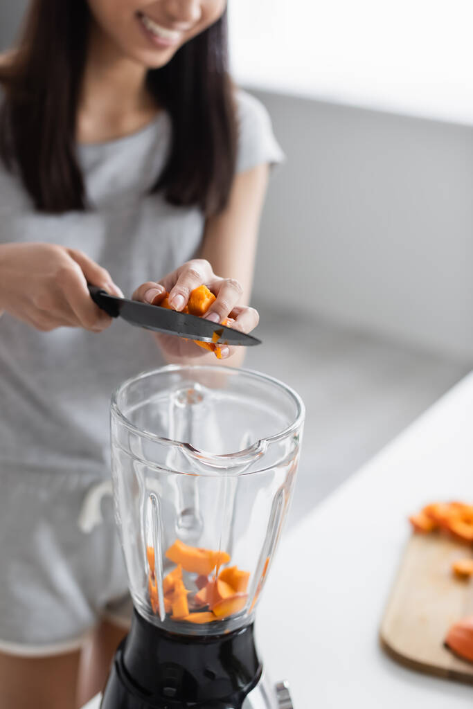 partial view of blurred woman with knife adding cut pumpkin into shaker - Photo, Image