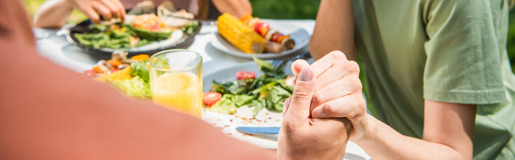 Vágott kilátás szülők kéz a kézben közelében gyerek és elmosódott élelmiszer a szabadban, banner  - Fotó, kép