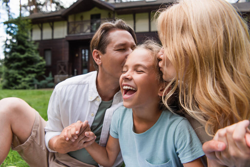 Rodiče líbání vzrušené dítě venku  - Fotografie, Obrázek