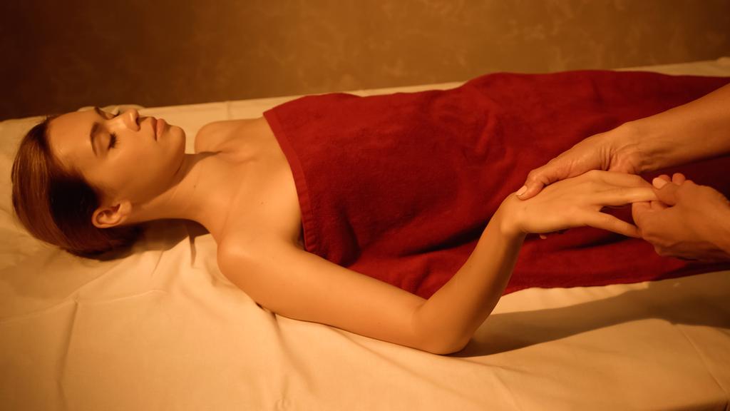 giovane cliente con gli occhi chiusi che riceve massaggio alle mani dal massaggiatore nel salone spa - Foto, immagini