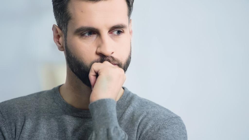 stresszes és szakállas férfi néz félre, miközben otthon gondolkodik - Fotó, kép