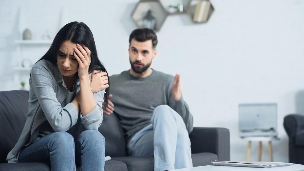 frustrated woman sitting near blurred and displeased boyfriend  - Photo, Image