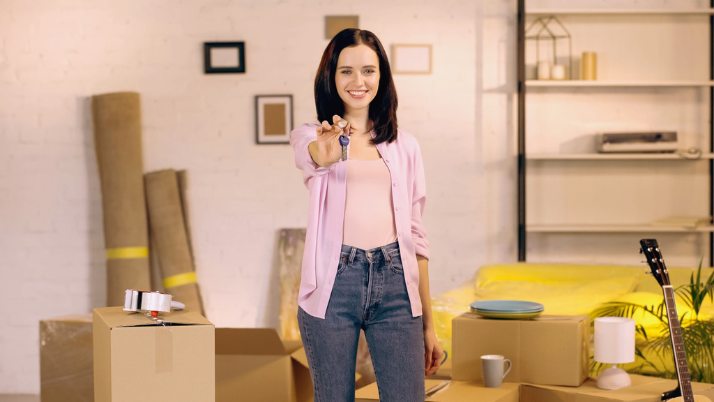glückliche junge Frau zeigt Schlüssel vor der Kamera im neuen Zuhause - Foto, Bild
