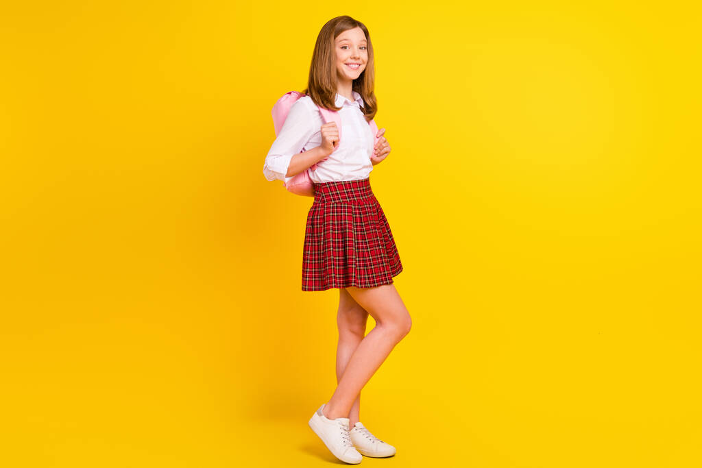 Pleine longueur photo de belle blonde petite fille stand porter chemise jupe sac baskets isolé sur fond de couleur jaune - Photo, image
