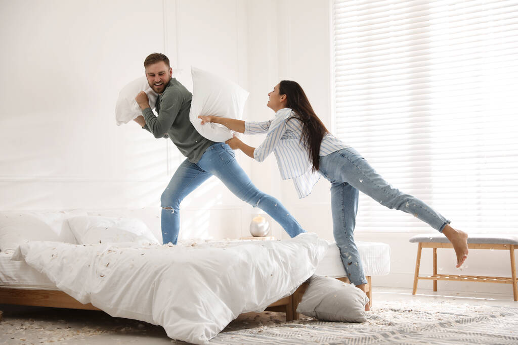 Счастливая молодая пара веселится битва подушками в спальне - Фото, изображение