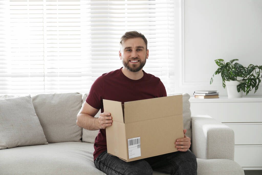 Šťastný mladý muž s balíčkem doma - Fotografie, Obrázek