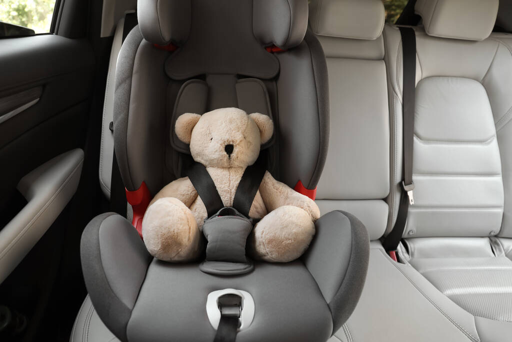 Oso de peluche abrochado con cinturón de seguridad para automóvil en asiento infantil - Foto, imagen