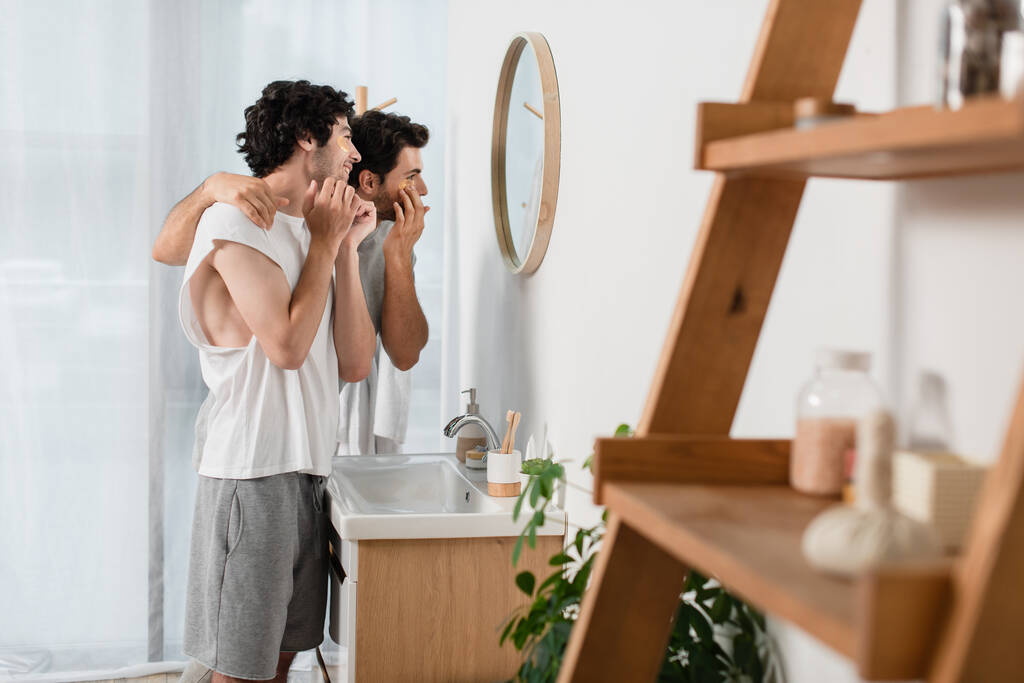 fröhliches homosexuelles Paar trägt Augenklappen im Badezimmer auf - Foto, Bild