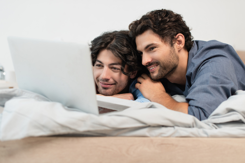 楽しいゲイのカップル見ます映画上のラップトップでベッドルーム  - 写真・画像