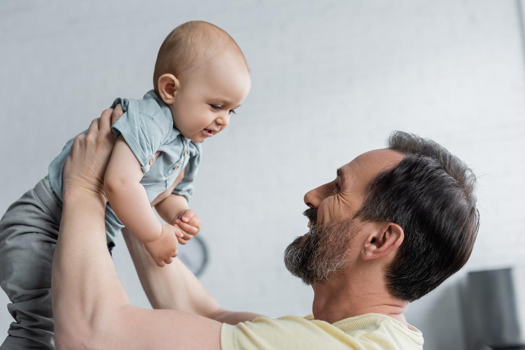 Side view of cheerful father holding baby daughter  - Photo, Image