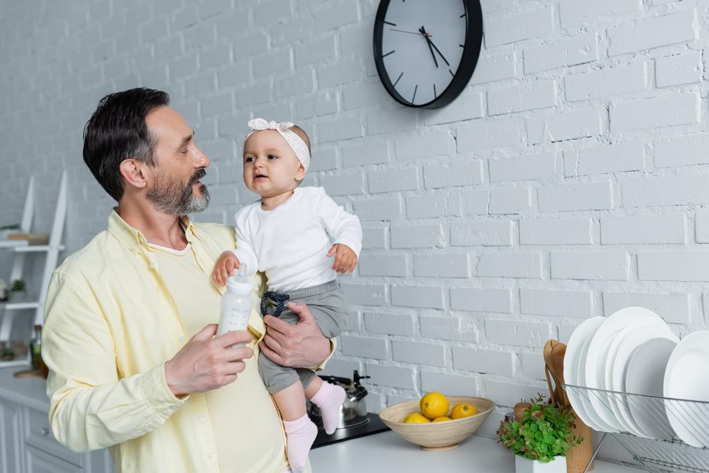熟女保有赤ちゃん娘とボトルのミルクでキッチン  - 写真・画像