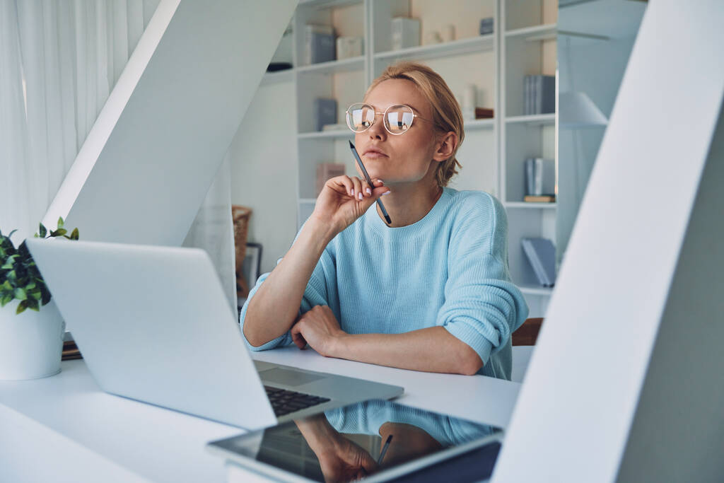 Gyönyörű fiatal nő használja laptop és néz figyelmes, miközben dolgozik az irodában - Fotó, kép