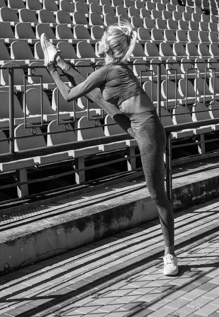 sexy Frau Stretching im Freien. athletische Frau im Sportbekleidungstraining auf dem Stadion. Beim Aufwärmen ihrer Muskeln. weiblichen flexiblen Körper. Yoga und Pilates. Sport einen gesunden Lebensstil. fitness coach - Foto, Bild