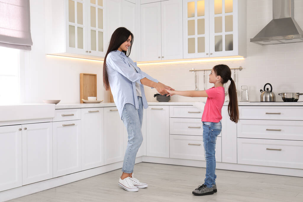 Счастливая мать и дочь танцуют вместе на кухне. Одинокое воспитание - Фото, изображение